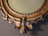 a picture of a mirror with a gold frame on the wall