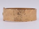gros plan d'un bracelet en or sur une surface blanche