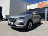 une Nissan QX argentée garée devant un immeuble