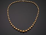 a gold beaded necklace on a black background