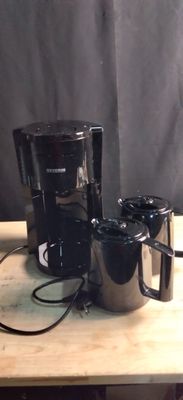 une cafetière et deux tasses posées sur une table en bois