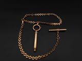 un collier en or avec une clé et une chaîne sur fond noir