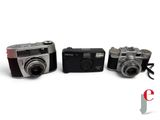 three cameras sitting next to each other on a white surface