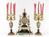 three candles and a clock sitting on a table