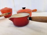 three pots with wooden handles sitting on a table