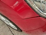 a close up of a red car that has a dent in it