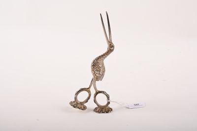 une sculpture en argent représentant un oiseau avec des ciseaux à l'intérieur