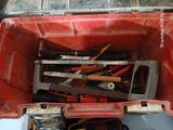 une boîte à outils rouge remplie d'outils, posée par terre