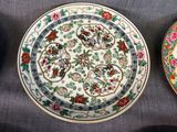 three plates with floral designs on them are sitting on a table
