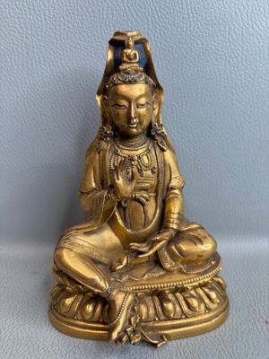 statue en laiton représentant une personne assise en position du lotus sur une table