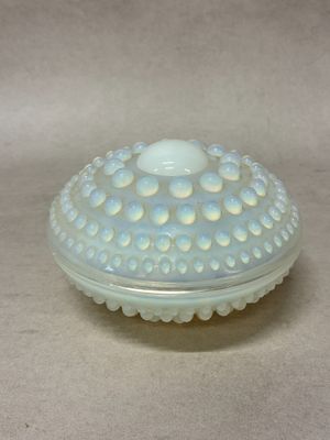 un petit bol en verre avec un couvercle posé sur une table