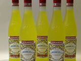 quatre bouteilles de limonade sont alignées sur une surface blanche