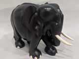statue of an elephant with tusks and tusks on a white surface