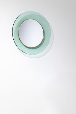 a round mirror on the wall above a sink