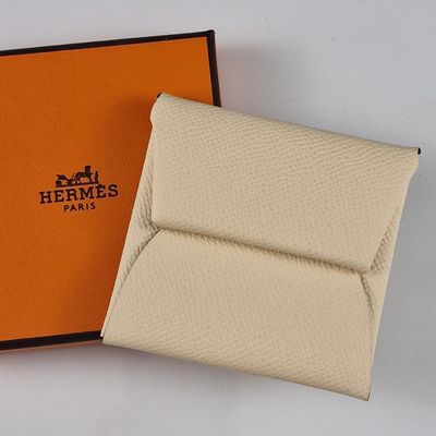 une boîte orange contenant un portefeuille blanc et une boîte noire avec un logo marron