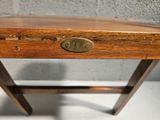 a small wooden table with a brass plate on it