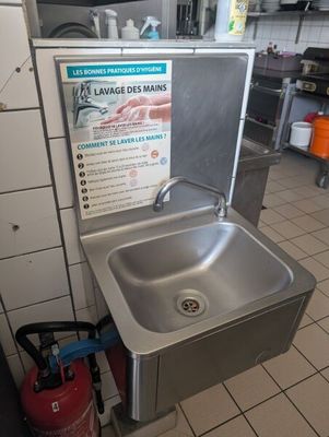 a stainless steel sink in a kitchen with a fire extinguisher next to it