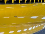 a man standing next to a yellow car with a yellow grill
