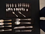 a lot of silver spoons and forks on a black table