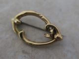 a small gold brooch on a marble surface