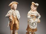 two figurines of a boy and a girl standing next to each other
