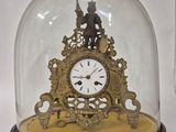 une petite horloge sous un dôme de verre sur une table