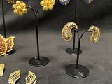 several different types of earrings and brooches on display on a black surface