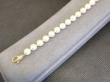bracelet en perles avec un fermoir en or, présenté dans un étui en velours gris