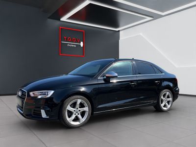 Une Audi noire est garée devant un immeuble.
