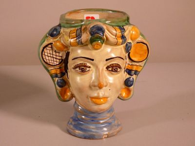 a ceramic head of a woman with a tennis racket on her head