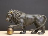 statue d'un lion tenant une balle entre ses pattes, posée sur une table