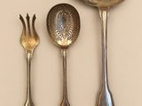 three spoons, a fork, and a spoon rest on a table