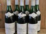 six bottles of wine are lined up on a wooden shelf