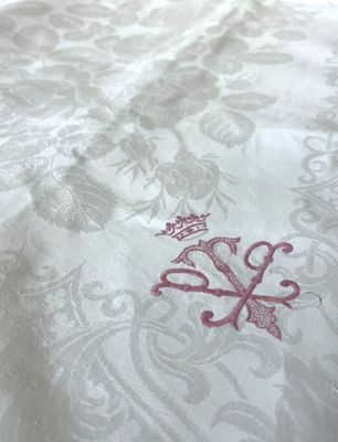 un gros plan d'un lit recouvert d'une couette blanche sur laquelle est posée une couronne rouge