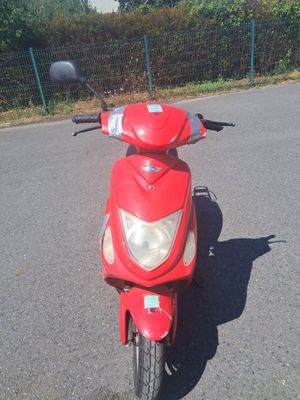 un scooter rouge garé sur un parking