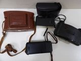 three cameras and a camera case on a white table
