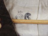a stuffed animal sitting on a pillow with a wooden stick