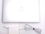 a white apple laptop computer with a charger and a cable