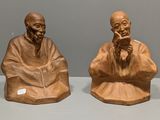 deux figurines représentant des vieillards assis sur une table, sur fond gris