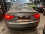 une voiture argentée garée dans un garage, avec d'autres voitures en arrière-plan