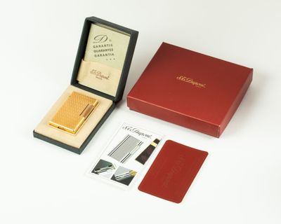 a red box with a gold lighter and a card in it