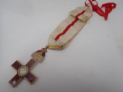 a gold cross with a red ribbon and a clock on it