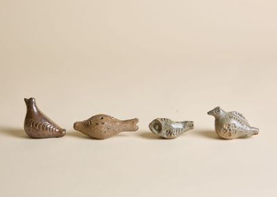 trois petits oiseaux en céramique assis les uns à côté des autres sur une surface blanche