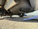 un avion en papier posé par terre à côté d'une voiture