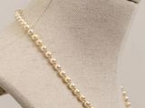 a close up of a mannequin with a pearl necklace on it