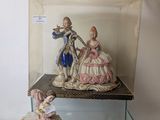 two figurines of people sitting on a glass shelf