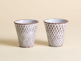 une paire de tasses en céramique blanches et marron sur fond beige
