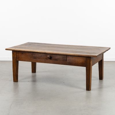 une vieille table basse en bois surmontée d'un tiroir