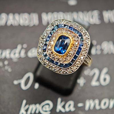 un gros plan d'une bague sertie d'un diamant et d'un saphir posée sur une feuille de papier