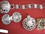 a lot of silver bracelets and brooches on a red cloth
